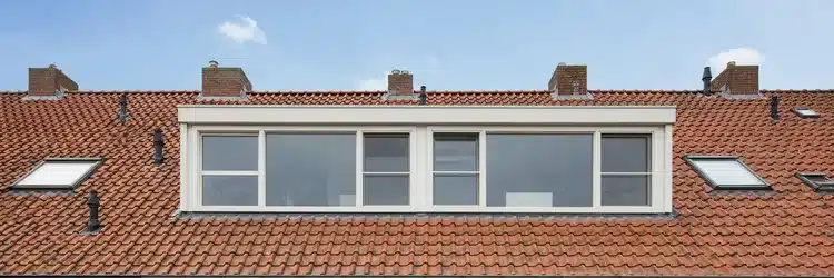 Brede dakkapel over twee kamers op een schuin dak met pannendak