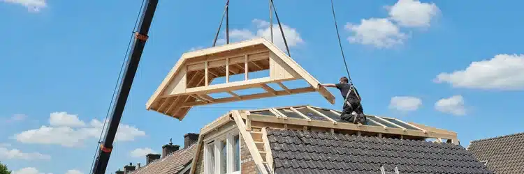 Prefab nokverhoging wordt met een kraan op een Nederlands schuin dak geplaatst